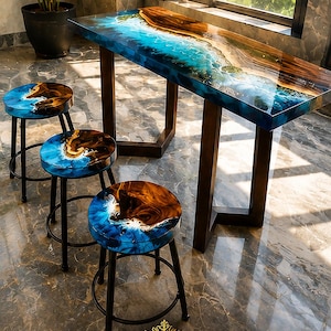 Könnte beinhalten: Ein rechteckiger Tisch und drei runde Hocker mit einem Naturholzkanten-Design, kombiniert mit blauem Harz, das Meereswellen nachahmt. Das Möbelset hat dunkle Metallbeine und eine glänzende Oberfläche. Text unten: GlowstoneInlayArtIN.
