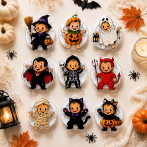 May include: A set of nine circular acrylic charms featuring illustrations of babies in various Halloween costumes, including a witch, pumpkin, ghost, vampire, skeleton, devil, mummy, black cat, and a baby wearing a pumpkin-themed outfit.