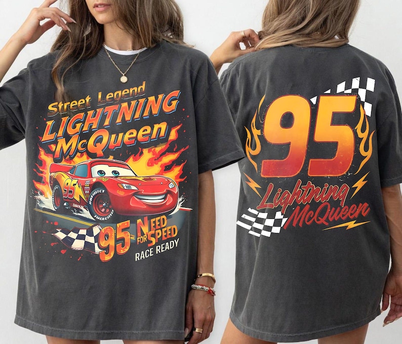 May include: Charcoal grey t-shirt with a Lightning McQueen design. The front features the red race car with flames and the text "Street Legend Lightning McQueen". The back displays the number 95 and the text "Lightning McQueen".