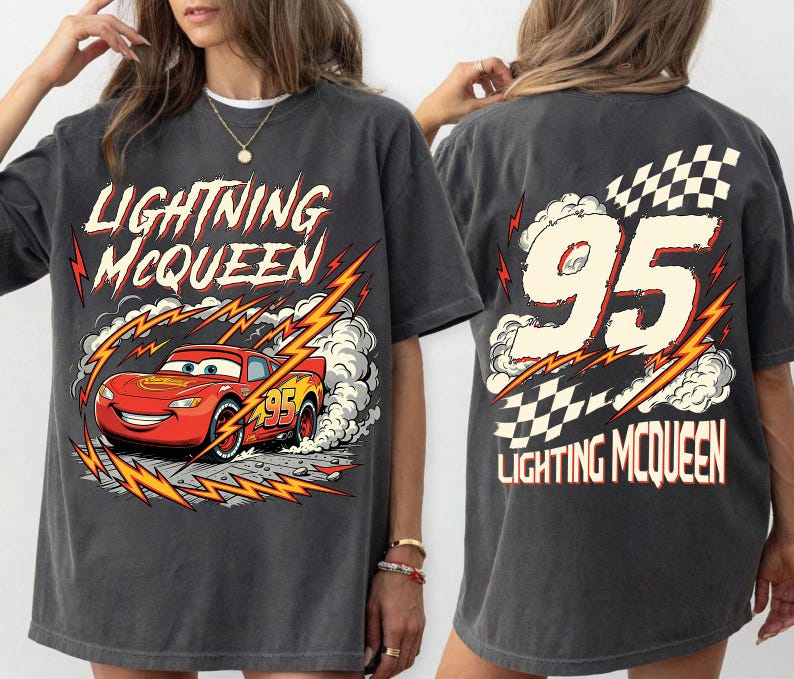 May include: Dark gray t-shirt featuring Lightning McQueen from the Cars movie. The front graphic shows McQueen racing with lightning bolts and the text "Lightning McQueen". The back displays the number "95" with a checkered flag.