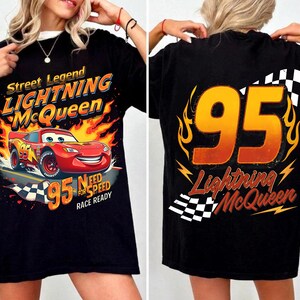 May include: Black t-shirt featuring Lightning McQueen from the movie Cars. The front graphic shows McQueen racing with flames and the text "Street Legend Lightning McQueen". The back displays the number 95 and the name Lightning McQueen.