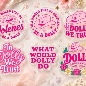 May include: Six clear acrylic stickers featuring pink and white designs. Text includes: In a world full of Jolenes be a Dolly, In a world full of Jolenes be a Dolly, In Dolly we trust, What would Dolly do, and Dolly forever & always 1946-2026.