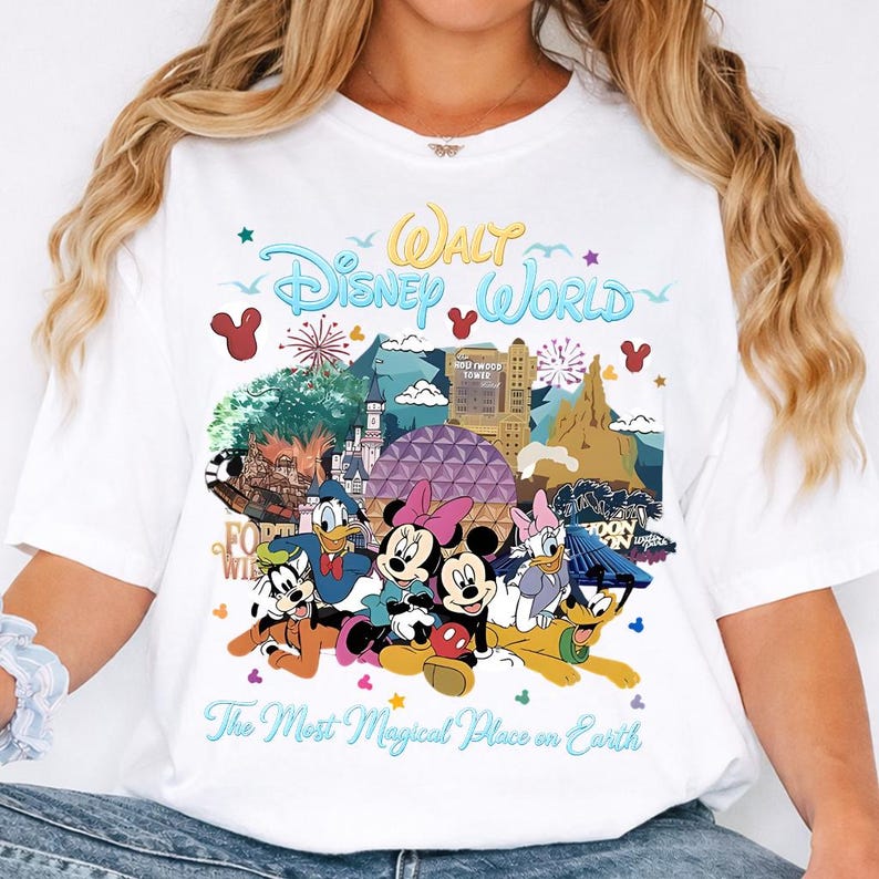 K&ouml;nnte beinhalten: Wei&szlig;es T-Shirt mit einem farbenfrohen Grafikdesign von Disney-Figuren und Wahrzeichen. Der Aufdruck enth&auml;lt den Text "Walt Disney World" und "The Most Magical Place on Earth". Das Shirt zeigt Mickey und Minnie Mouse.