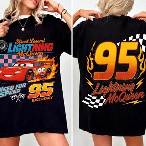 May include: Black t-shirt featuring Lightning McQueen from the movie Cars. The front graphic includes the text "Street Legend Lightning McQueen", a red race car, and the number 95. The back displays the number 95 and "Lightning McQueen".