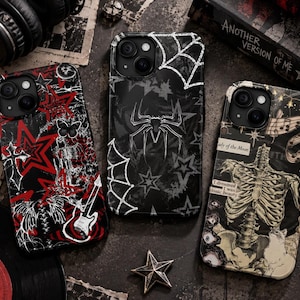 May include: Three smartphone cases featuring distinct graphic designs. The left case displays red stars, a guitar, and a butterfly. The center case features a spider and web motif. The right case shows a human rib cage illustration with text.