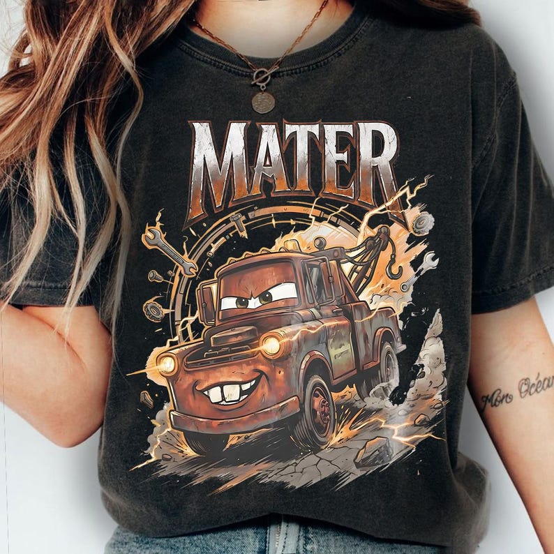 May include: Dark gray t-shirt featuring a cartoon image of Mater from the movie Cars. The word "MATER" is printed above the image in a distressed orange and white font. The image includes lightning bolts and tools.