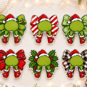 May include: Six decorative acrylic ornaments shaped like bows, each featuring a green furry character wearing a red Santa hat and red boots. The bows have varied patterns including green with lights, red and white stripes, snowflakes, red with lights, holly leaves with berries, and black and white plaid.