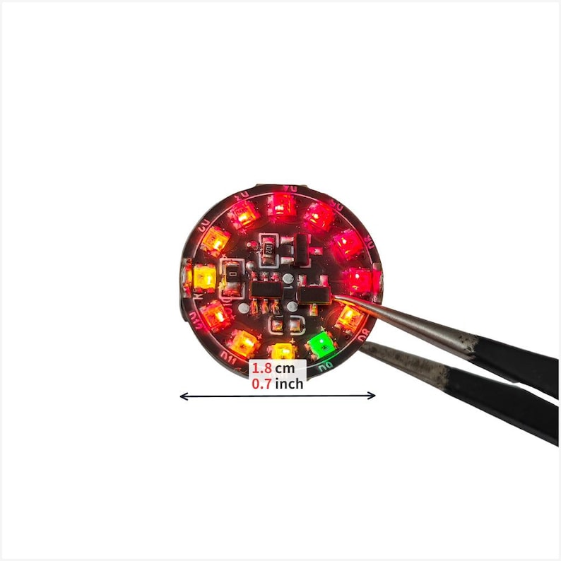 Puede incluir: Una placa de circuito impreso circular negra con m&uacute;ltiples LED rojos, naranjas y verdes iluminados dispuestos en anillo. El componente mide 1,8 cm de di&aacute;metro, seg&uacute;n lo indicado por el texto y el gr&aacute;fico de doble flecha.
