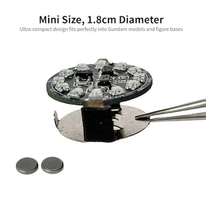 Puede incluir: Un circuito impreso circular negro con m&uacute;ltiples componentes LED peque&ntilde;os y una base de contacto met&aacute;lica para bater&iacute;a. El texto dice: Mini Size, 1.8cm Diameter. Ultra-compact design fits perfectly into Gundam models and figure bases. Dos peque&ntilde;as bater&iacute;as de bot&oacute;n plateadas se muestran en la parte inferior.