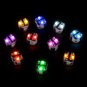 May include: Ten multi-coloured LED lights are displayed. Each light has a silver base and a square top with four bright LEDs. The colours include yellow, blue, white, purple, red, pink, green, and orange, set against a black backdrop.