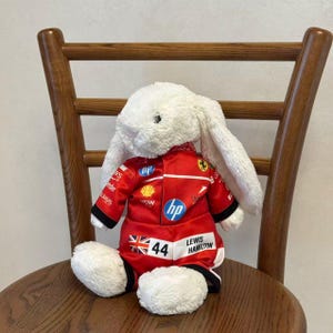 Side view of a bunny plush wearing a red one-piece racing jumpsuit, showing the sleeve fit, leg openings and sporty collector styling; clothes only, plush not included.