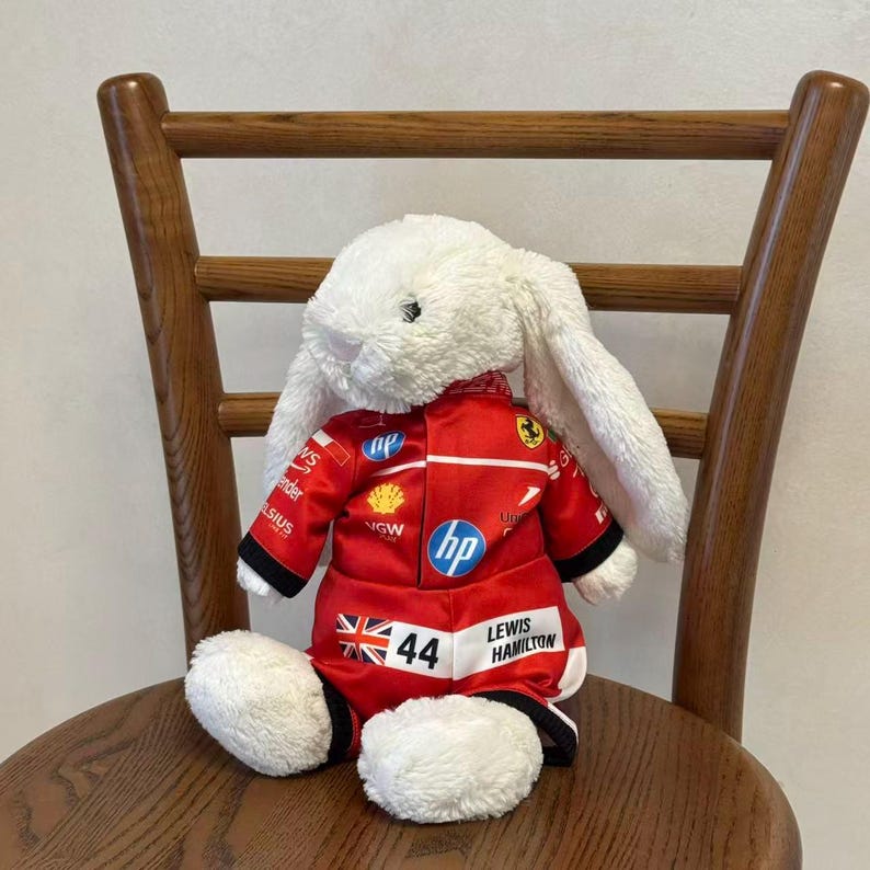 Side view of a bunny plush wearing a red one-piece racing jumpsuit, showing the sleeve fit, leg openings and sporty collector styling; clothes only, plush not included.