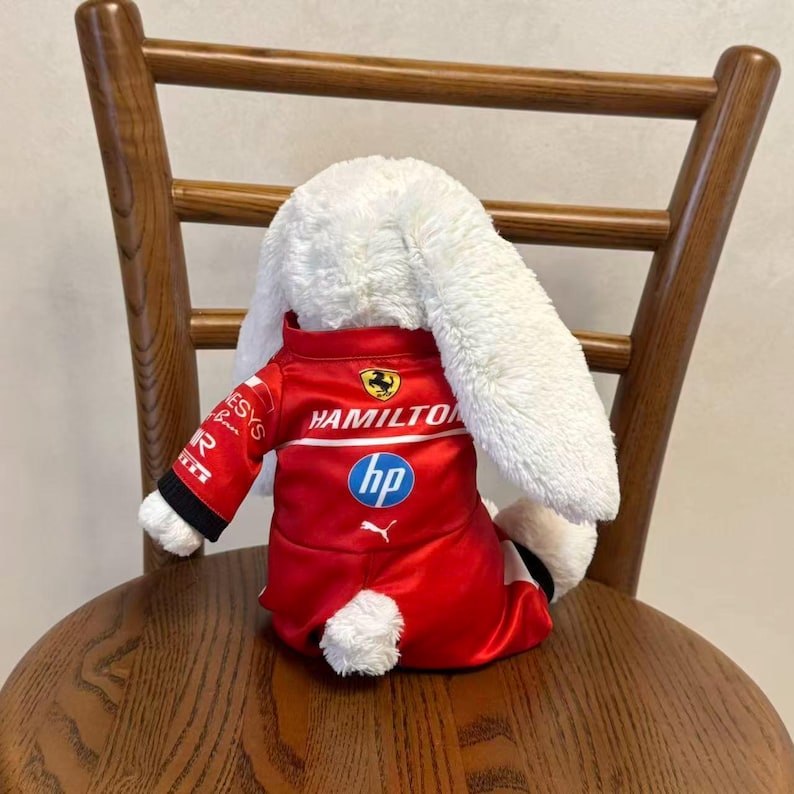 Back view of a red racing jumpsuit for bunny plush, showing the rear fit, high collar and one-piece design for stuffed animal display and photography; plush not included.