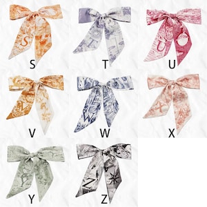May include: Collection of silk scarves in various colors, each tied in a bow. The scarves feature unique patterns and the letters S, T, U, V, W, X, Y, and Z. Colors include orange, lavender, pink, brown, navy, peach, sage green, and black and white.
