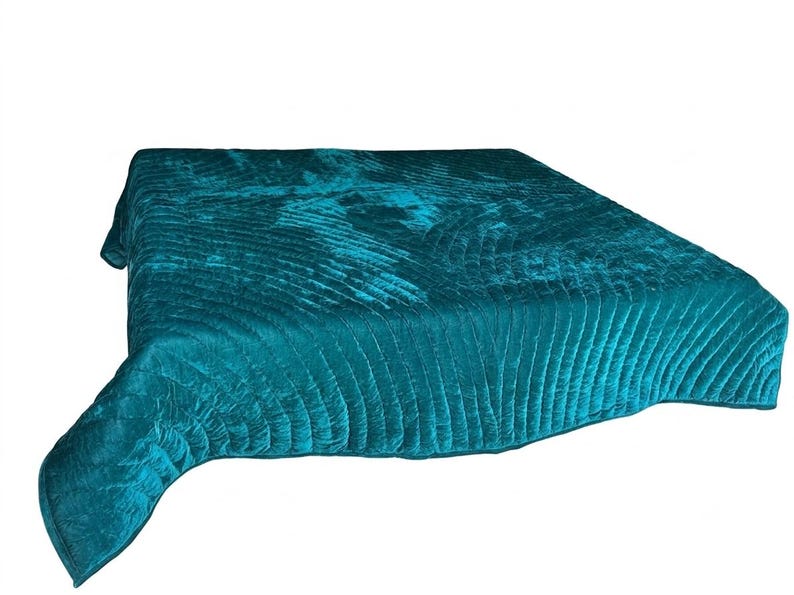 May include: A rectangular teal velvet quilt featuring a repeating fan-shaped stitched pattern across the surface. The fabric has a soft, reflective sheen characteristic of velvet, with deep blue-green tones and a finished edge border.