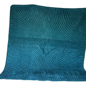 May include: A square teal velvet quilt featuring a repeating fan-shaped stitched pattern that radiates from the center. The fabric has a soft, light-reflecting texture with deep blue-green tones and a finished edge border surrounding the quilted design.