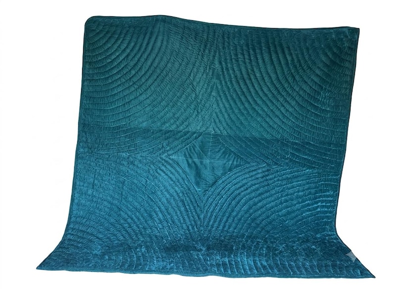May include: A square teal velvet quilt featuring a repeating fan-shaped stitched pattern that radiates from the center. The fabric has a soft, light-reflecting texture with deep blue-green tones and a finished edge border surrounding the quilted design.