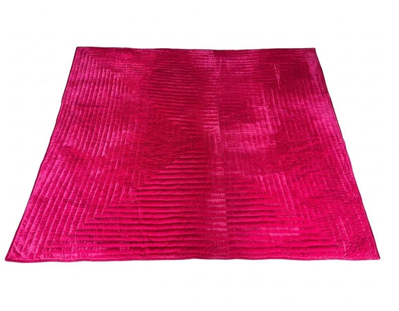 Puede incluir: Un edred&oacute;n grande y rectangular de color rosa intenso con un patr&oacute;n geom&eacute;trico. El edred&oacute;n tiene una superficie acolchada y texturizada con l&iacute;neas rectas que crean un dise&ntilde;o visual. Los bordes est&aacute;n cuidadosamente acabados y el edred&oacute;n est&aacute; sobre un fondo blanco.