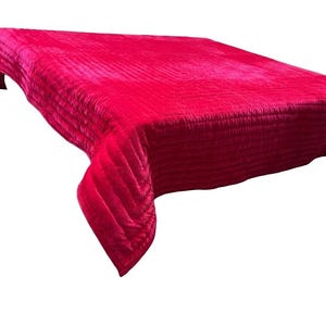 Puede incluir: Una colcha fucsia brillante con un dise&ntilde;o acolchado. La tela tiene una textura suave y aterciopelada, y la colcha est&aacute; drapeada sobre una superficie, mostrando su forma y textura. La est&eacute;tica general es lujosa y acogedora.