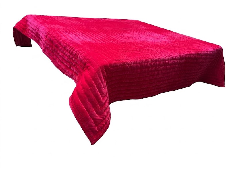 Puede incluir: Una colcha fucsia brillante con un dise&ntilde;o acolchado. La tela tiene una textura suave y aterciopelada, y la colcha est&aacute; drapeada sobre una superficie, mostrando su forma y textura. La est&eacute;tica general es lujosa y acogedora.