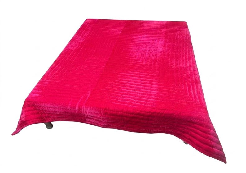 Puede incluir: Un edred&oacute;n fucsia vibrante con un patr&oacute;n acolchado texturizado. El edred&oacute;n rectangular est&aacute; drapeado sobre una superficie, mostrando su rico color y dise&ntilde;o. Los bordes del edred&oacute;n son ligeramente curvos.