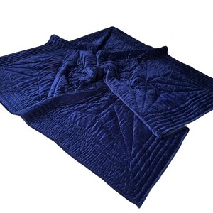 May include: A deep navy blue velvet quilt featuring a geometric star pattern created by intricate channel stitching. The fabric has a soft, plush texture with a subtle sheen, and the edges are finished with a wide, quilted border design.