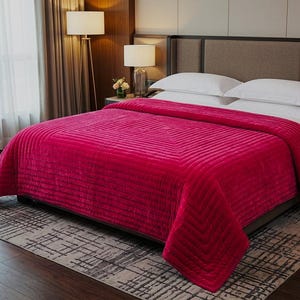 Puede incluir: Un edred&oacute;n fucsia vibrante con un patr&oacute;n geom&eacute;trico cubre una cama con almohadas blancas. El edred&oacute;n texturizado es el punto focal, agregando un toque de color al dormitorio. La cama est&aacute; sobre una alfombra estampada.