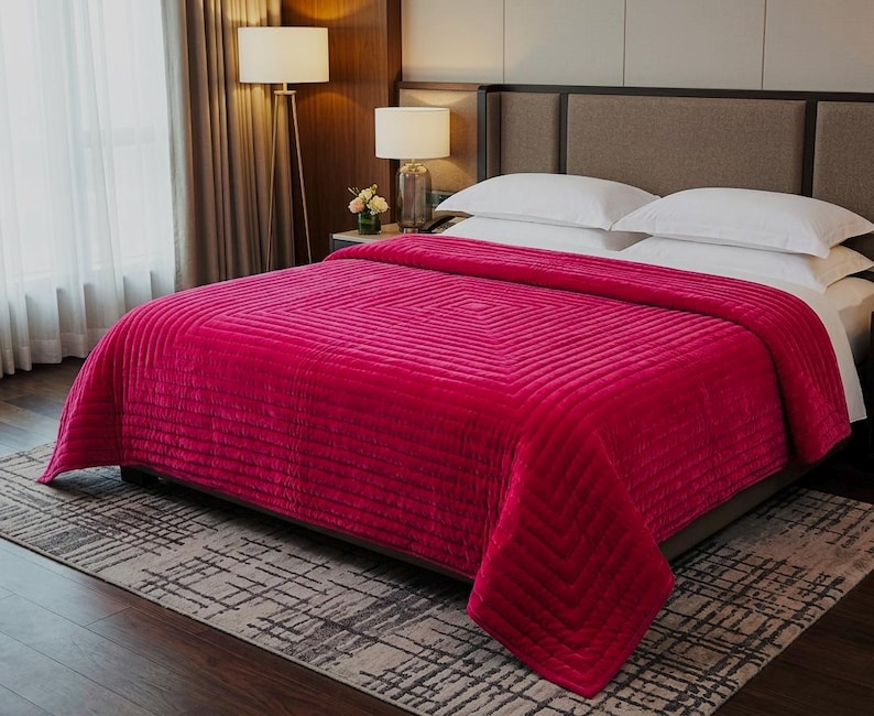 Puede incluir: Un edred&oacute;n fucsia vibrante con un patr&oacute;n geom&eacute;trico cubre una cama con almohadas blancas. El edred&oacute;n texturizado es el punto focal, agregando un toque de color al dormitorio. La cama est&aacute; sobre una alfombra estampada.