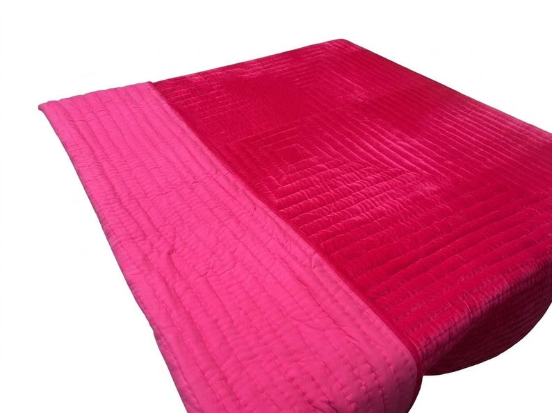 Puede incluir: Una manta acolchada de dos tonos en tonos rosa y rojo. La manta presenta un patr&oacute;n cosido con una secci&oacute;n rosa m&aacute;s clara a la izquierda y una secci&oacute;n roja m&aacute;s oscura a la derecha. La textura parece suave y afelpada.