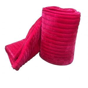 Puede incluir: Una manta rosa brillante enrollada, con un dise&ntilde;o acolchado. La manta, hecha de un material suave y afelpado, est&aacute; parcialmente desenrollada, mostrando su textura y color. Dise&ntilde;ada para brindar comodidad y calidez.
