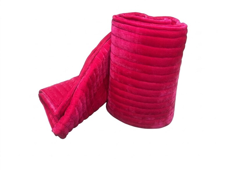 Puede incluir: Una manta rosa brillante enrollada, con un dise&ntilde;o acolchado. La manta, hecha de un material suave y afelpado, est&aacute; parcialmente desenrollada, mostrando su textura y color. Dise&ntilde;ada para brindar comodidad y calidez.