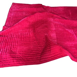 Puede incluir: Un edred&oacute;n de color fucsia vibrante con un patr&oacute;n geom&eacute;trico. El edred&oacute;n est&aacute; hecho de un material suave y aterciopelado y presenta un dise&ntilde;o cosido que crea una superficie texturizada. Los bordes est&aacute;n cuidadosamente acabados y el edred&oacute;n est&aacute; doblado.
