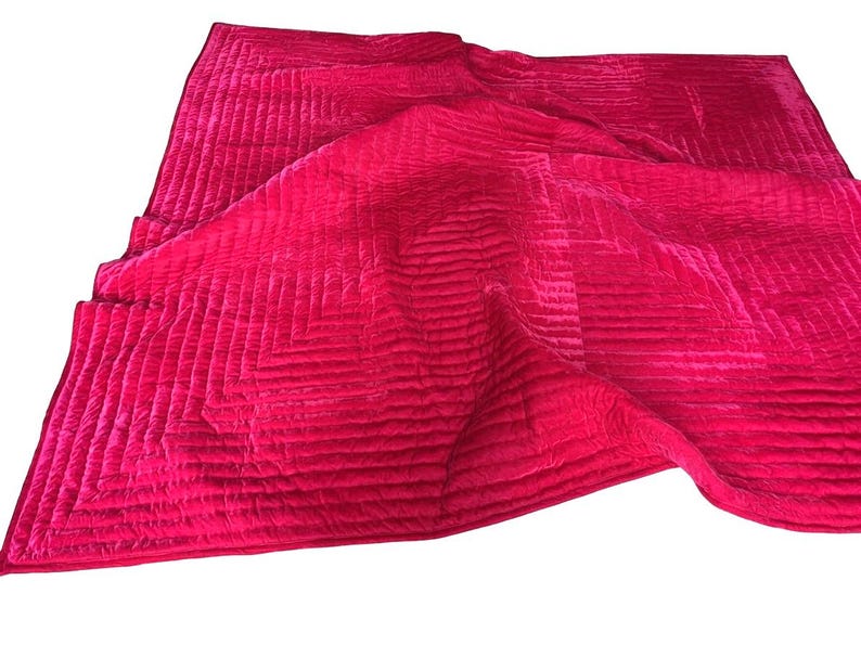 Puede incluir: Un edred&oacute;n de color fucsia vibrante con un patr&oacute;n geom&eacute;trico. El edred&oacute;n est&aacute; hecho de un material suave y aterciopelado y presenta un dise&ntilde;o cosido que crea una superficie texturizada. Los bordes est&aacute;n cuidadosamente acabados y el edred&oacute;n est&aacute; doblado.