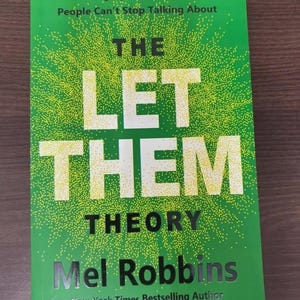 Puede incluir: Una portada de libro con fondo verde y el t&iacute;tulo "THE LET THEM THEORY" en letras blancas grandes. El nombre del autor, Mel Robbins, est&aacute; en plata, con el texto "New York Times Bestselling Author" debajo.