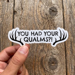 May include: A white die-cut sticker with a black border featuring the text "YOU HAD YOUR QUALMS?!" in a bold, sans-serif font. The design is flanked on both the left and right sides by black silhouettes of deer antlers extending outward.