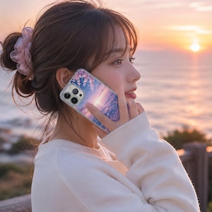 May include: A smartphone case featuring a printed design of a sunset sky with pink cherry blossom branches. The case has a clear border and a cutout for a multi-lens camera system, showcasing a vibrant gradient of purple, pink, and orange hues.