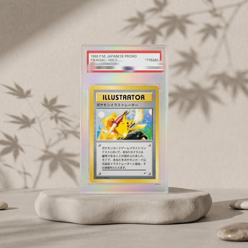 Puede incluir: Una tarjeta coleccionable hologr&aacute;fica japonesa "Pikachu Illustrator" de 1998, clasificada y sellada en una funda de pl&aacute;stico transparente. La tarjeta presenta una ilustraci&oacute;n de Pikachu sosteniendo un pincel y un bol&iacute;grafo, con el texto "ILLUSTRATOR" y caracteres japoneses.