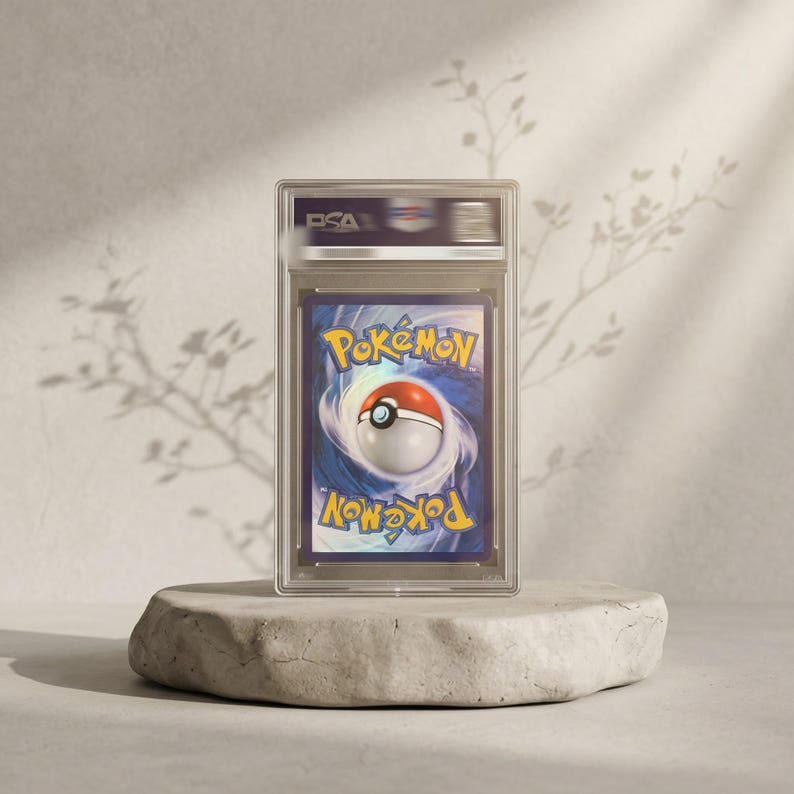 May include: A PSA graded Pok&eacute;mon trading card featuring the iconic blue and yellow logo with a central Pok&eacute; Ball graphic. The card is encased in a clear, rectangular protective plastic slab with the PSA logo clearly visible at the top section.