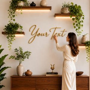 Könnte beinhalten: Eine Frau installiert goldfarbene Holzbuchstaben mit der Aufschrift "Your Text" an einer weißen Wand. Die Wand ist mit Holzregalen, Pflanzen und einem Holzschrank dekoriert. Die Szene ist gut beleuchtet und hat eine moderne, minimalistische Ästhetik.