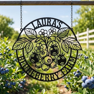 May include: A circular black metal sign featuring a cutout design of blueberry branches with leaves and berries. The text LAURA'S BLUEBERRY FARM is integrated into the circular frame. The sign hangs from two metal chains attached to a wooden bar.