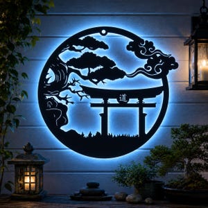 Könnte beinhalten: Ein kreisförmiges Wandkunstobjekt aus schwarzem Metall mit einer hinterleuchteten Silhouette eines Torii-Tors, eines Bonsai-Baums und stilisierter Wolken. In der Mitte des Torii-Tors ist das japanische Kanji für den Weg oder Pfad, Tao, zu sehen.