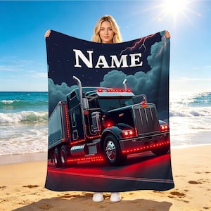 Puede incluir: Una manta rectangular que muestra un cielo nocturno azul oscuro con nubes y un rayo. Un camión semirremolque negro con luces rojas brillantes aparece en la carretera. La palabra "NAME" está impresa en letras blancas grandes arriba.