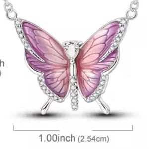 May include: A silver-toned butterfly pendant necklace. The butterfly has pink and purple wings with a crystal center and crystal accents along the edges. The butterfly measures 1.00 inch (2.54cm) wide and 0.82 inch (2.08cm) high.