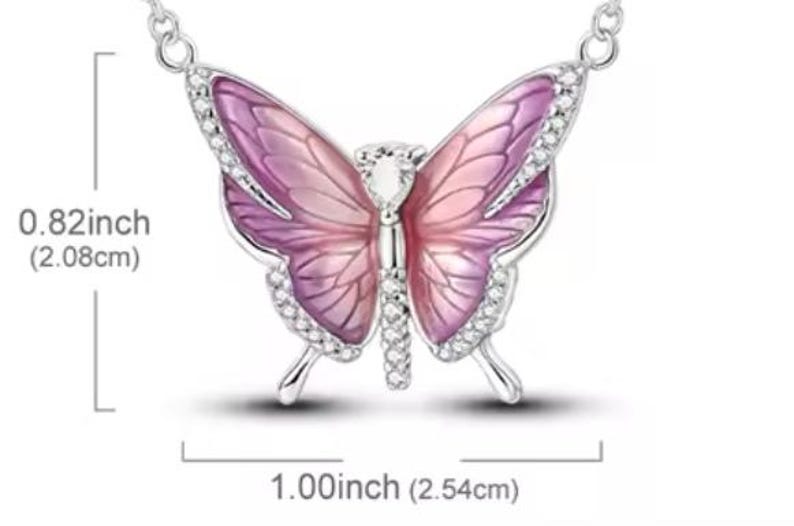 May include: A silver-toned butterfly pendant necklace. The butterfly has pink and purple wings with a crystal center and crystal accents along the edges. The butterfly measures 1.00 inch (2.54cm) wide and 0.82 inch (2.08cm) high.