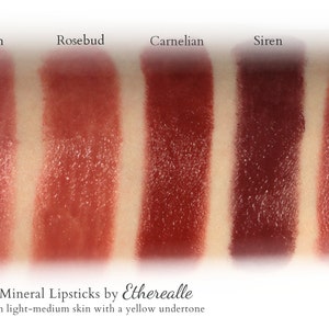 May include: Five different shades of vegan mineral lipstick swatches on light-medium skin with a yellow undertone. The shades are labeled: Nymph, Rosebud, Carnelian, Siren, and Spice. Vegan Mineral Lipsticks by Etherealle. Shown on light-medium skin with a yellow undertone.