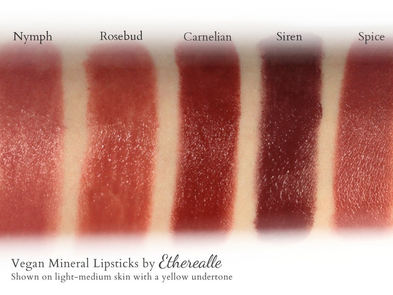 May include: Five different shades of vegan mineral lipstick swatches on light-medium skin with a yellow undertone. The shades are labeled: Nymph, Rosebud, Carnelian, Siren, and Spice. Vegan Mineral Lipsticks by Etherealle. Shown on light-medium skin with a yellow undertone.