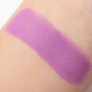 May include: A close-up of a light purple eyeshadow swatch on skin. The eyeshadow has a matte finish and is smooth and even.