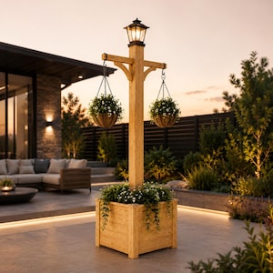 May include: A tall wooden post with a square planter base and a black lantern on top. Two hanging baskets with green plants are suspended from metal hooks on the crossbar. The planter is filled with green foliage and small white flowers.