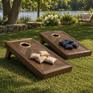 Könnte beinhalten: Zwei hölzerne Cornhole-Boards mit einem dunkelbraunen Fischgrätenmuster und einem kreisförmigen, messingumrandeten Loch. Auf einem Board liegen vier beige Stoff-Sitzsäcke, auf dem anderen vier marineblaue Stoff-Sitzsäcke.