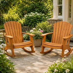 May include: Two wooden rocking chairs with a natural light brown finish, featuring curved backrests with vertical slats, wide armrests, and curved rockers, positioned on a stone patio with a potted plant placed between them.